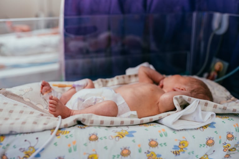 An infant sleeping in the bed of an NICU