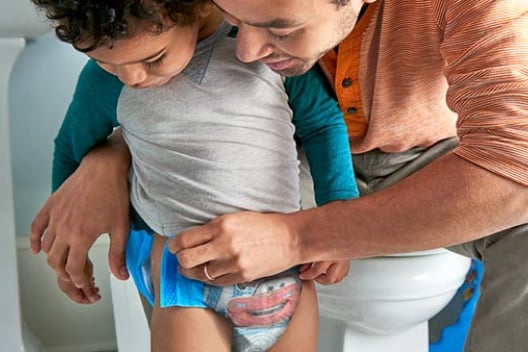 A father helping their baby in opening the Pull-ups Training Pants in the toilet