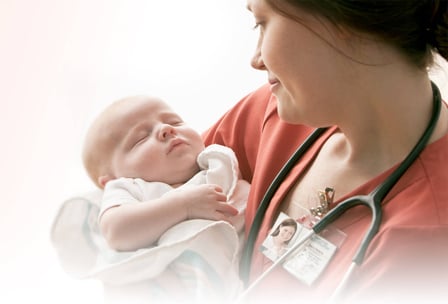 A nurse holding a sleeping newborn baby in her arms