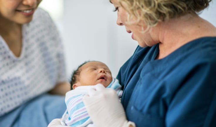 A Healthcare worker holding a newborn baby in her arms