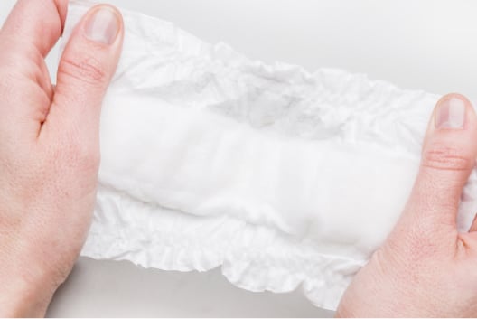 Hands demonstrating narrow absorbent pad on Huggies Little Snugglers Micro Preemie Diapers