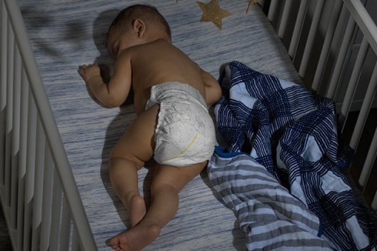 A Diapered baby sleeping in their bed